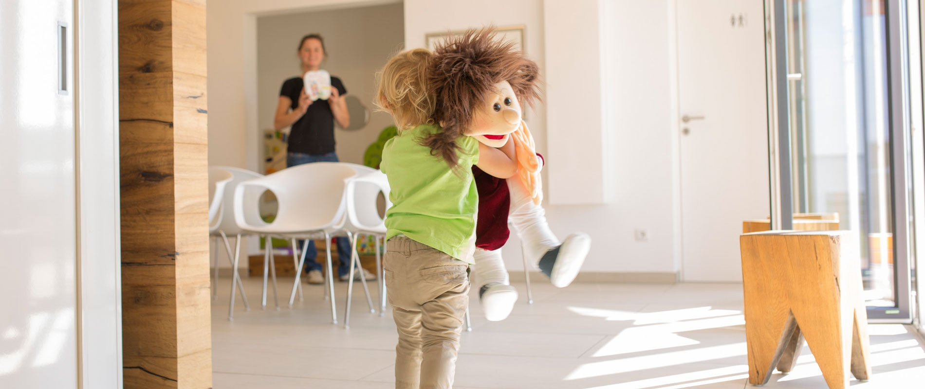 Kind spielt mit Puppe im Wartezimmer der Zahnarztpraxis.